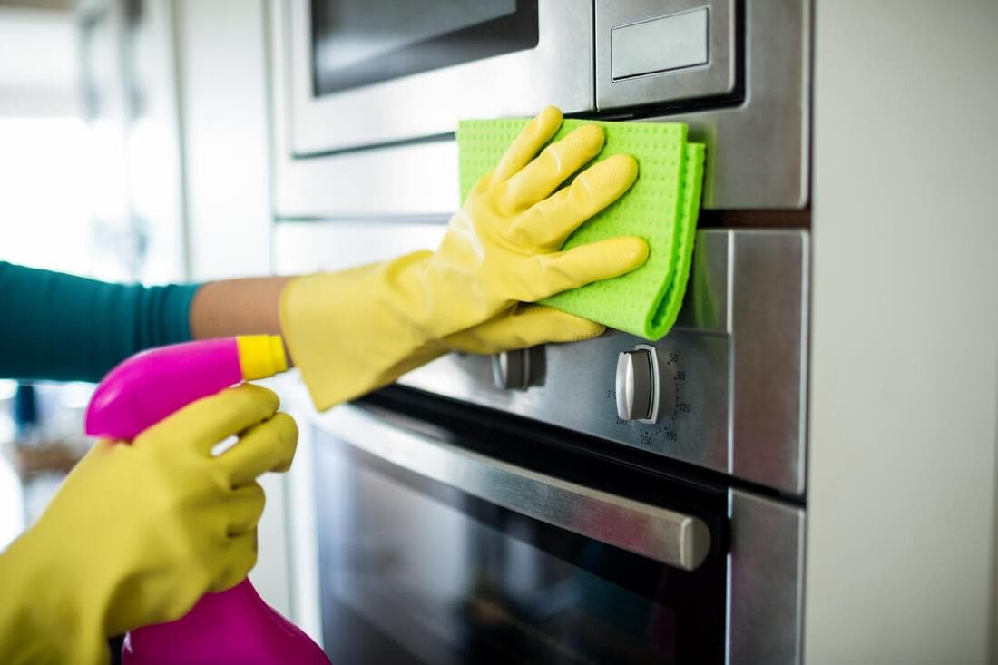 a picture of a a cleaner cleaning a metal gas stove