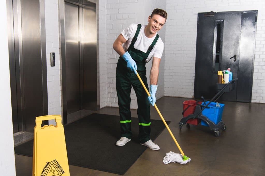 smiling janitor cleaning the front of elevators