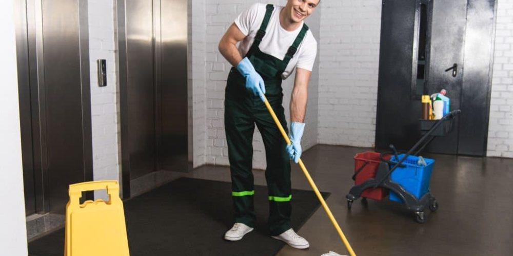 smiling janitor cleaning the front of elevators